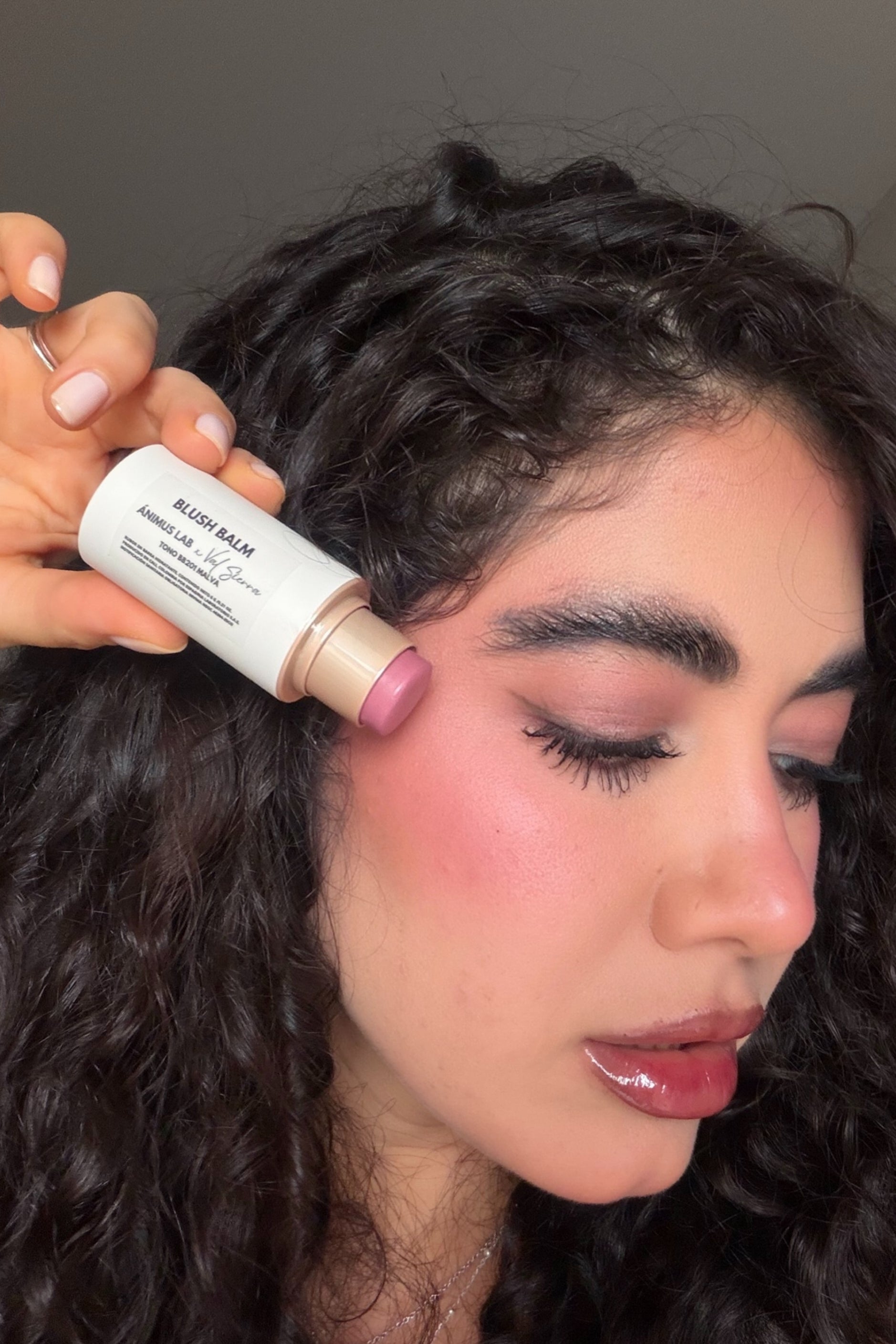 Blush Balm — modelo aplicando el rubor en barra en la mejilla